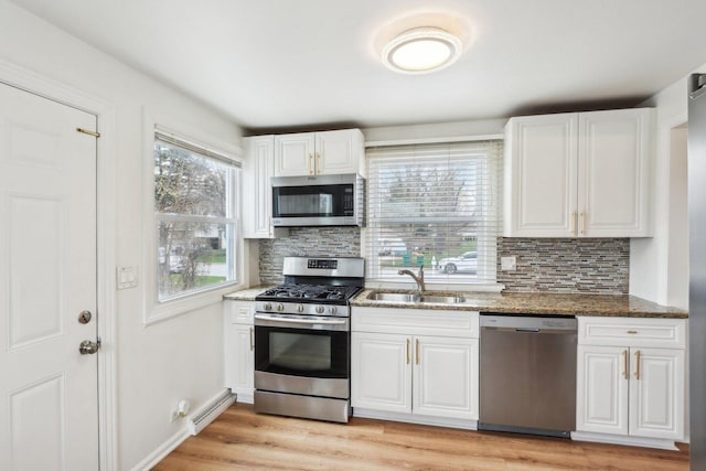 kitchen with stone countertops, a sink, appliances with stainless steel finishes, and decorative backsplash