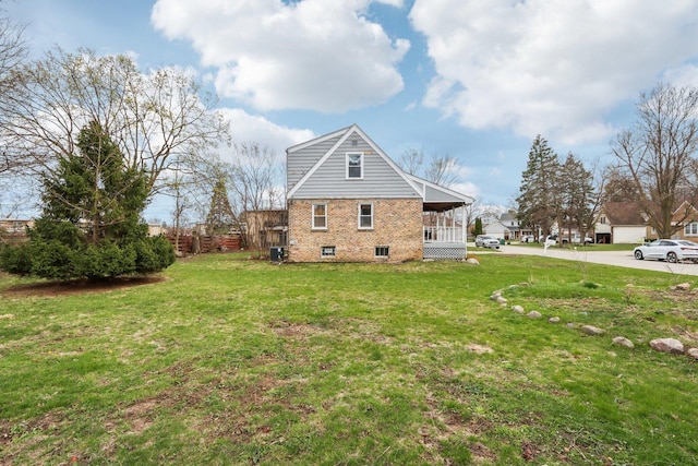 view of side of property featuring a lawn, central AC, and brick siding
