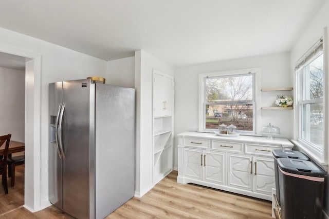 kitchen featuring light wood-style floors, stainless steel fridge, open shelves, white cabinetry, and light countertops