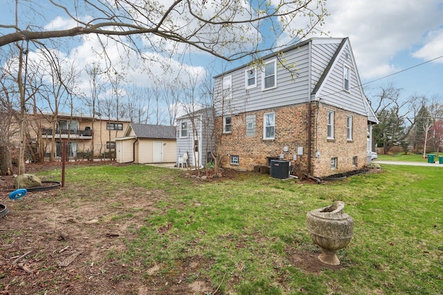 back of house with an outdoor structure, a shed, a lawn, central AC, and brick siding