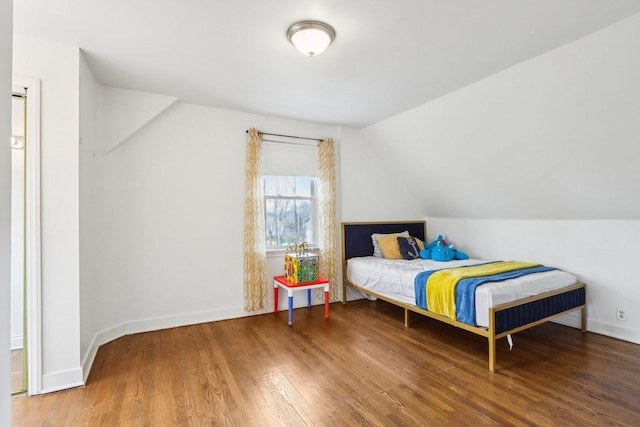 bedroom featuring wood finished floors, vaulted ceiling, and baseboards