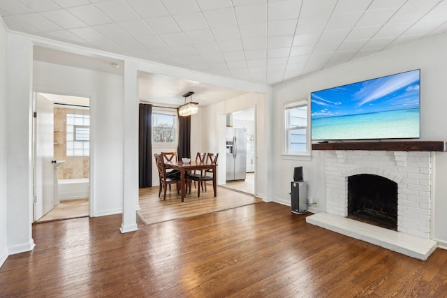 living room featuring a brick fireplace, wood finished floors, and baseboards