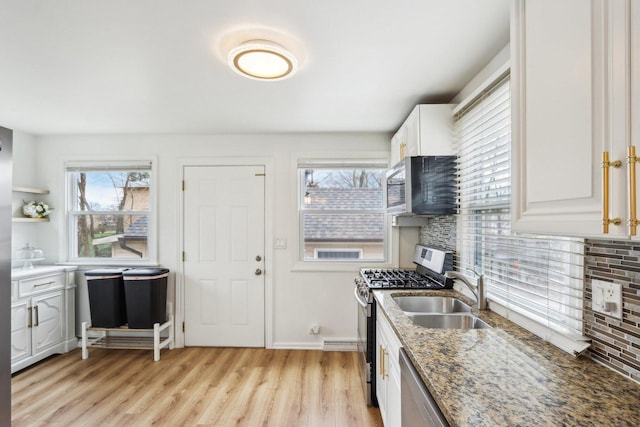 kitchen with a wealth of natural light, appliances with stainless steel finishes, light wood-style flooring, and a sink
