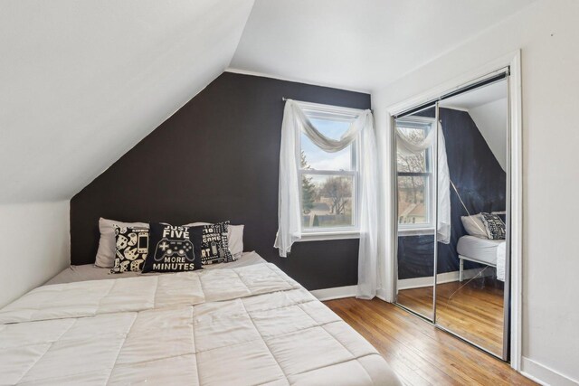 bedroom with lofted ceiling, wood finished floors, and baseboards