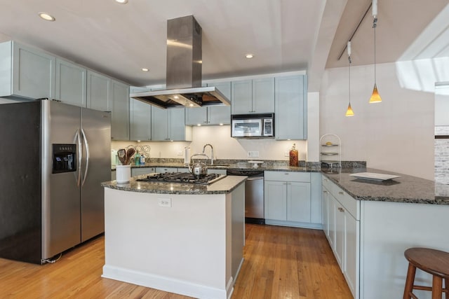 kitchen featuring stainless steel appliances, island range hood, light wood-type flooring, dark stone countertops, and recessed lighting