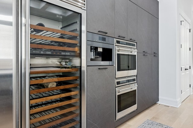 1431 N Mohawk St, Chicago, IL 60610 - kitchen with wine cooler, light wood finished floors, gray cabinets, stainless steel double oven, and modern cabinets