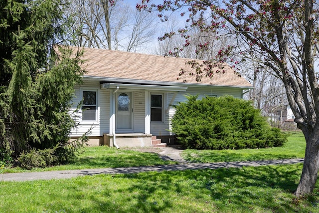 view of front of property featuring a shingled roof and a front lawn