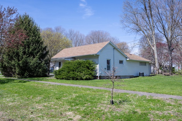 view of side of home featuring a lawn, cooling unit, and roof with shingles