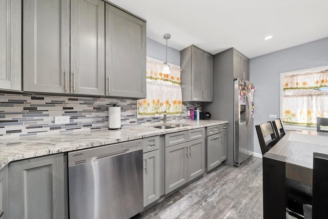 kitchen with stainless steel appliances, gray cabinetry, a sink, light wood-style flooring, and recessed lighting
