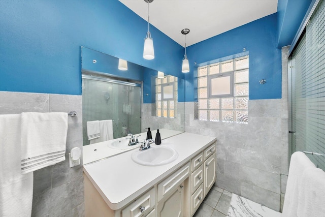 bathroom featuring tile walls, a stall shower, wainscoting, and vanity