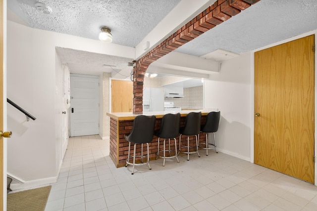 7324 W Lunt Ave, Chicago, IL 60631 - bar featuring a textured ceiling, light tile patterned floors, a dry bar, baseboards, and under cabinet range hood