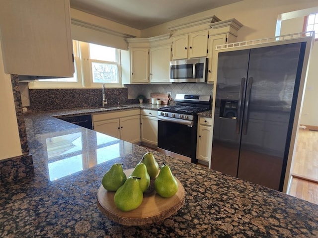 7324 W Lunt Ave, Chicago, IL 60631 - kitchen with dark stone countertops, a sink, decorative backsplash, appliances with stainless steel finishes, and white cabinetry