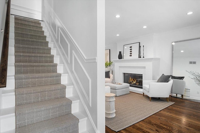 staircase with a glass covered fireplace, recessed lighting, wood finished floors, and visible vents