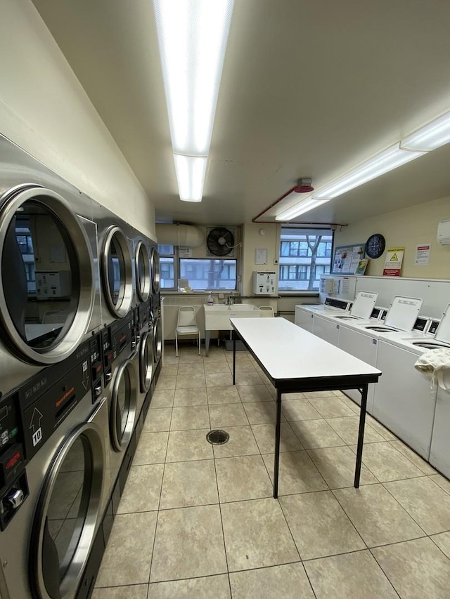 community laundry room with light tile patterned floors, stacked washer / drying machine, and washer and clothes dryer