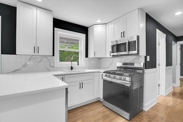 314 W 106th Pl, Chicago, IL 60628 - kitchen with stainless steel appliances, a sink, white cabinets, light wood finished floors, and recessed lighting