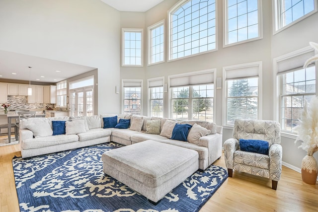 living room featuring baseboards, a high ceiling, recessed lighting, and light wood-style floors