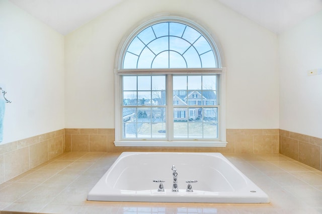 bathroom with a bath, a wealth of natural light, and vaulted ceiling