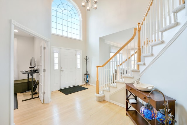 entryway with stairs, wood finished floors, a towering ceiling, and plenty of natural light