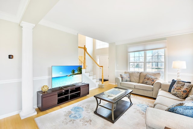 living area with baseboards, ornate columns, wood finished floors, stairway, and ornamental molding