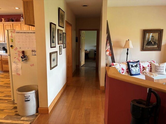 hallway with baseboards, light wood-style floors, and recessed lighting