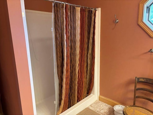 bathroom with toilet, a shower with shower curtain, and baseboards