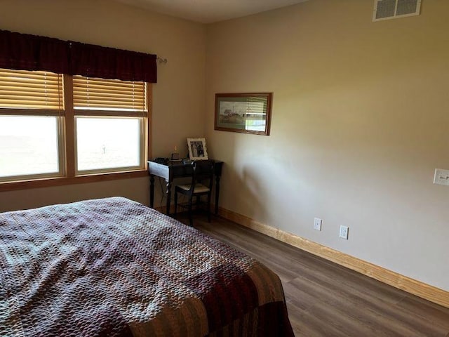 bedroom with wood finished floors, visible vents, and baseboards