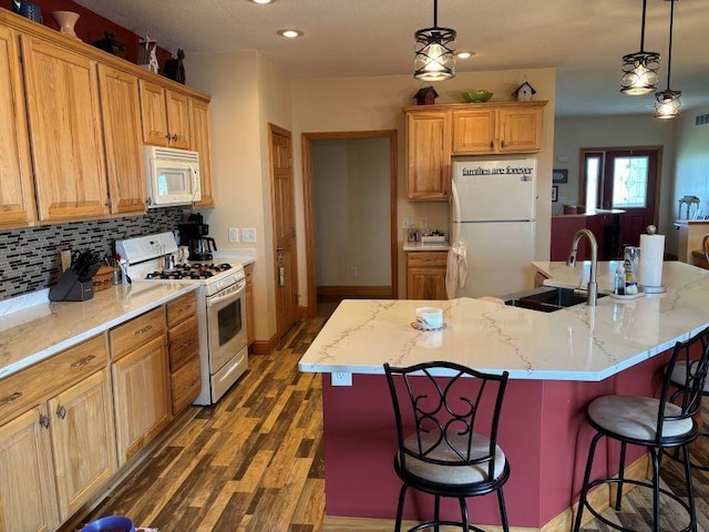 kitchen with a breakfast bar, white appliances, a sink, and dark wood finished floors