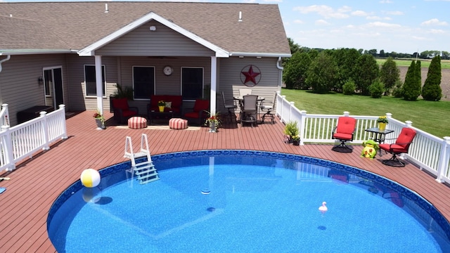outdoor pool with a yard, outdoor dining space, and a deck