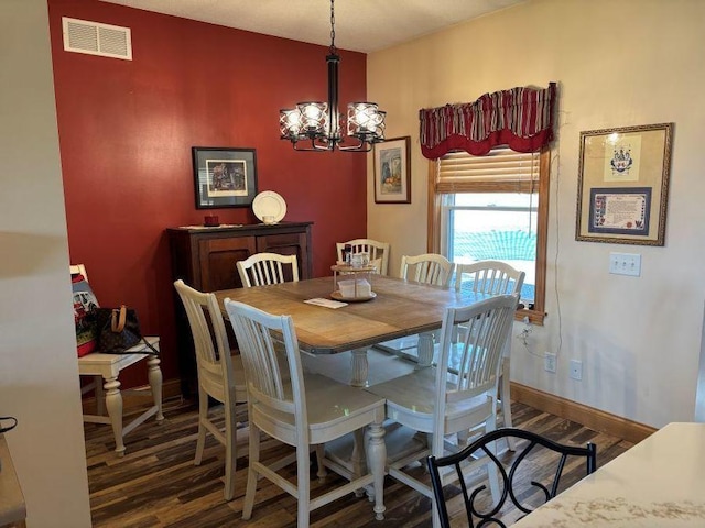 dining space featuring a chandelier, wood finished floors, visible vents, and baseboards
