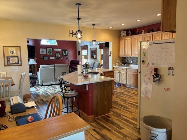 kitchen featuring a sink, open floor plan, freestanding refrigerator, light countertops, and dark wood-type flooring