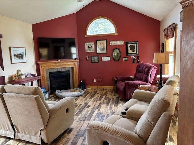 living room with baseboards, wood finished floors, a fireplace, and high vaulted ceiling