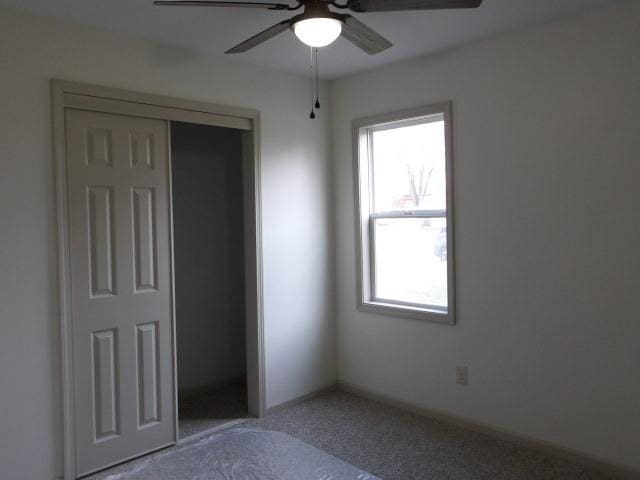 908 Merrill Ave, Loves Park, IL 61111 - unfurnished bedroom featuring a closet, carpet flooring, and a ceiling fan