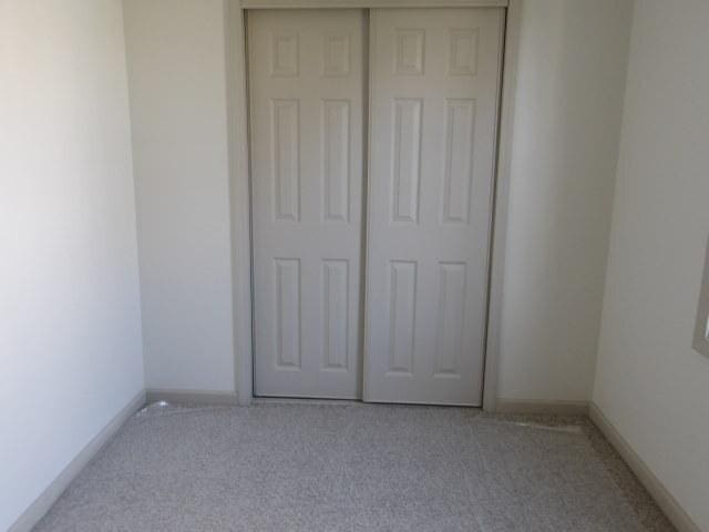908 Merrill Ave, Loves Park, IL 61111 - unfurnished bedroom with a closet, carpet flooring, and baseboards