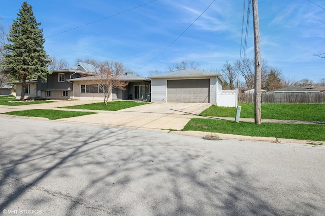 split level home with a front lawn, fence, driveway, and an attached garage