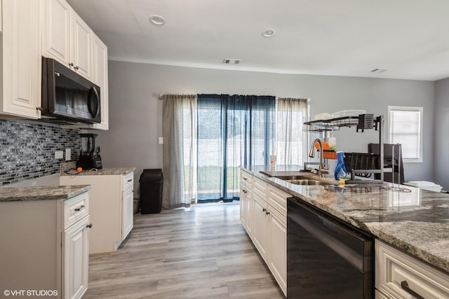 kitchen featuring black appliances, light stone countertops, a sink, and plenty of natural light