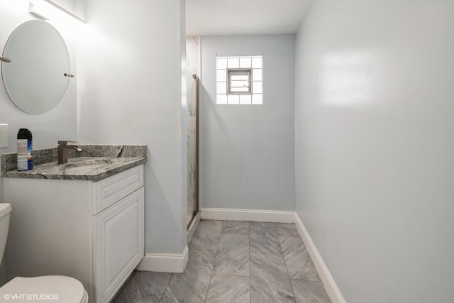 bathroom with baseboards, toilet, vanity, and a stall shower
