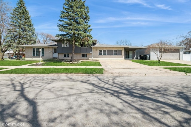 tri-level home featuring an outdoor structure, a front lawn, brick siding, and concrete driveway
