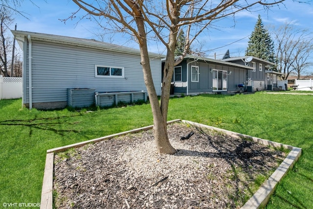 rear view of property with board and batten siding, a lawn, and fence