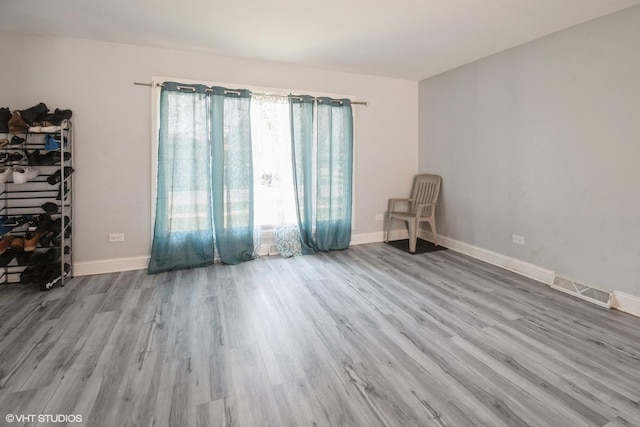 empty room featuring baseboards, wood finished floors, and visible vents