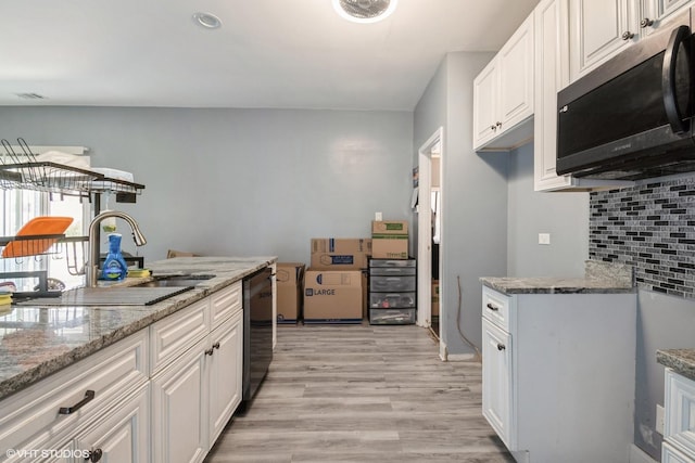 kitchen with a sink, light wood-style floors, backsplash, white cabinetry, and dishwashing machine