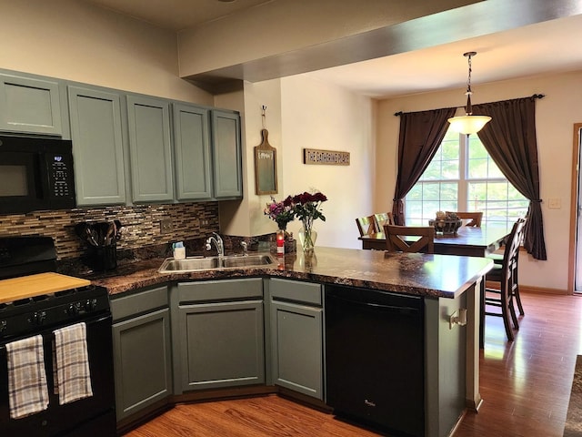 119 Oak Knoll Ct, Volo, IL 60020 - kitchen featuring black appliances, a peninsula, a sink, decorative backsplash, and wood finished floors
