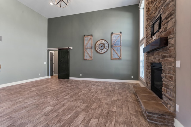 1101 Cascade Dr, Savoy, IL 61874 - unfurnished living room featuring a fireplace, a barn door, wood finished floors, and a towering ceiling