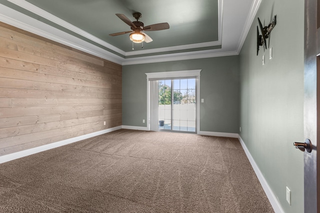 1101 Cascade Dr, Savoy, IL 61874 - empty room featuring a tray ceiling, wooden walls, a ceiling fan, carpet floors, and crown molding