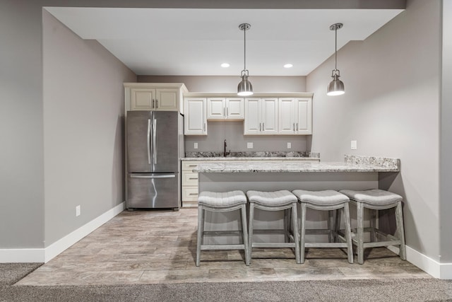1101 Cascade Dr, Savoy, IL 61874 - kitchen featuring freestanding refrigerator, a breakfast bar area, a peninsula, pendant lighting, and light wood-style floors