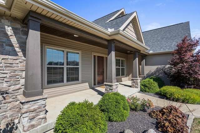 1101 Cascade Dr, Savoy, IL 61874 - view of exterior entry with stone siding, roof with shingles, and covered porch