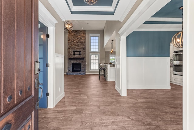 1101 Cascade Dr, Savoy, IL 61874 - entrance foyer featuring wood finished floors, a stone fireplace, a decorative wall, a chandelier, and ornamental molding