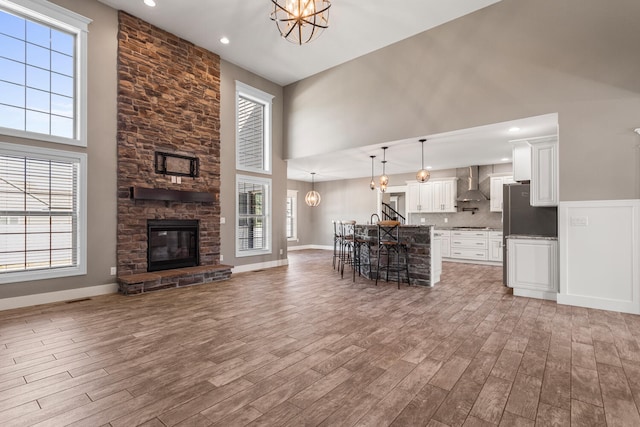 1101 Cascade Dr, Savoy, IL 61874 - living area featuring a chandelier, a high ceiling, wood finished floors, a stone fireplace, and recessed lighting