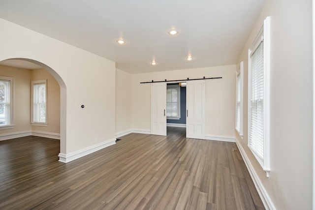 1005 Hovey Ave, Normal, IL 61761 - empty room with a barn door, dark wood-style flooring, and a healthy amount of sunlight
