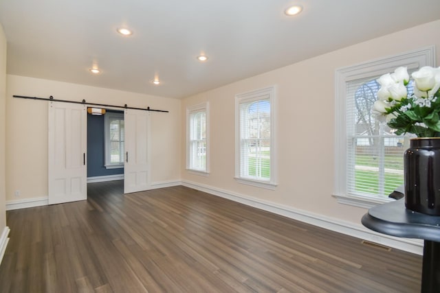 1005 Hovey Ave, Normal, IL 61761 - unfurnished bedroom with multiple windows, dark wood-type flooring, and a barn door