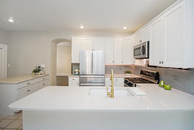 1005 Hovey Ave, Normal, IL 61761 - kitchen with arched walkways, light countertops, backsplash, a peninsula, and appliances with stainless steel finishes